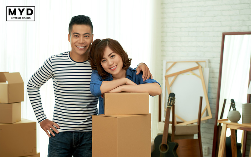 Happy couple with moving boxes in their new home.